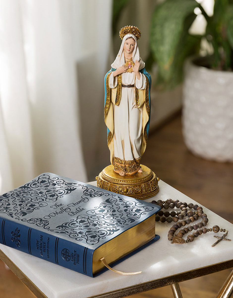 Virgin Mary Statue with bible and rosary on a table